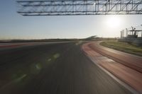 a car on a race track and the sun shining in the background as it passes by