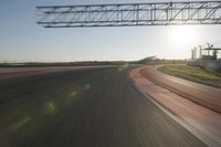 a car on a race track and the sun shining in the background as it passes by