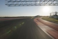 a car on a race track and the sun shining in the background as it passes by