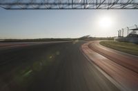 a car on a race track and the sun shining in the background as it passes by