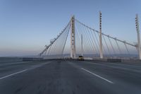 cars drive over the bridge and across it on a clear day, with blue skies above