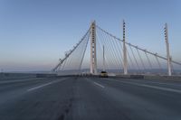 cars drive over the bridge and across it on a clear day, with blue skies above