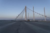 cars drive over the bridge and across it on a clear day, with blue skies above