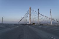 cars drive over the bridge and across it on a clear day, with blue skies above