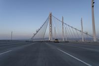 cars drive over the bridge and across it on a clear day, with blue skies above