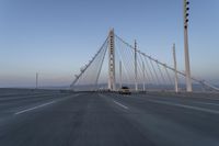 cars drive over the bridge and across it on a clear day, with blue skies above