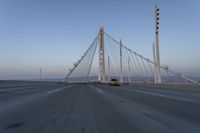 cars drive over the bridge and across it on a clear day, with blue skies above