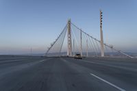 cars drive over the bridge and across it on a clear day, with blue skies above