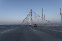 cars drive over the bridge and across it on a clear day, with blue skies above