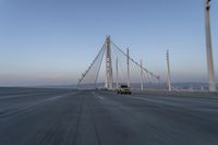 cars drive over the bridge and across it on a clear day, with blue skies above