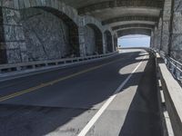 a couple of cars driving under an overpass on a bridge with large windows and a wall