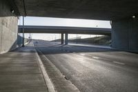 cars driving on an empty highway under a bridge at dusk or evening time time with sunlight