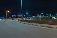 cars driving on the side of the road at night, passing lights and traffic posts