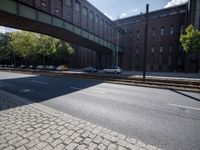cars are parked on a city street under an overpass, as if they were in an accident