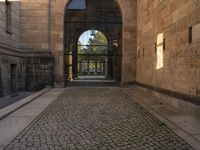 a cat that is sitting on the ground of a walkway near a building with an arched doorway