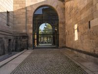 a cat that is sitting on the ground of a walkway near a building with an arched doorway