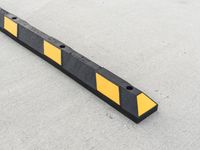 a small rectangular shaped yellow and black caution sign on a cement surface outside a building