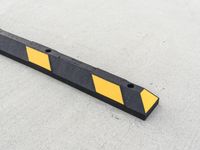 a small rectangular shaped yellow and black caution sign on a cement surface outside a building