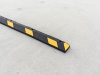 a small rectangular shaped yellow and black caution sign on a cement surface outside a building