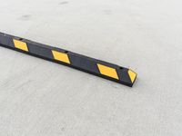 a small rectangular shaped yellow and black caution sign on a cement surface outside a building