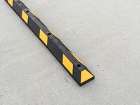 a small rectangular shaped yellow and black caution sign on a cement surface outside a building