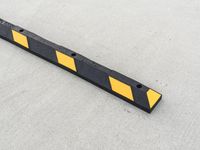 a small rectangular shaped yellow and black caution sign on a cement surface outside a building