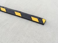 a small rectangular shaped yellow and black caution sign on a cement surface outside a building