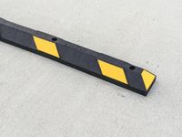 a small rectangular shaped yellow and black caution sign on a cement surface outside a building