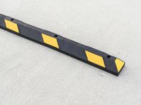 a small rectangular shaped yellow and black caution sign on a cement surface outside a building