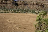 there is a person walking across a dirt field by the mountains on a sunny day