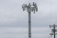 a cell phone tower with power lines and telephone towers on the roof over it,