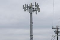 a cell phone tower with power lines and telephone towers on the roof over it,