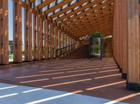 the underside beams of an outdoor wood pavilion structure overlooking water and hills with trees and grass