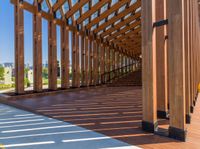 the underside beams of an outdoor wood pavilion structure overlooking water and hills with trees and grass