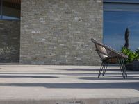 a chair sitting on the edge of concrete blocks in front of a building with trees and potted plants