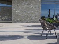 a chair sitting on the edge of concrete blocks in front of a building with trees and potted plants