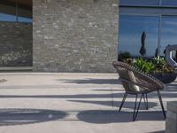 a chair sitting on the edge of concrete blocks in front of a building with trees and potted plants