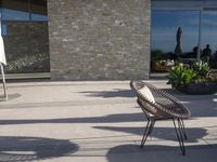 a chair sitting on the edge of concrete blocks in front of a building with trees and potted plants