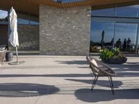 a chair sitting on the edge of concrete blocks in front of a building with trees and potted plants