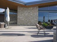 a chair sitting on the edge of concrete blocks in front of a building with trees and potted plants