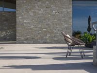 a chair sitting on the edge of concrete blocks in front of a building with trees and potted plants