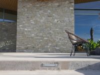 a chair sitting on the edge of concrete blocks in front of a building with trees and potted plants