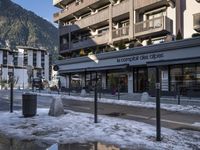 a bus station is surrounded by buildings on a road with snow on it's ground