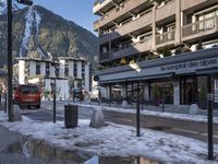 street with puddles and buildings in a ski resort area with snow on the ground