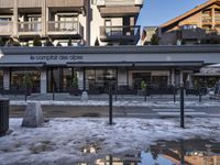 an outdoor restaurant covered with snow and surrounded by buildings of the ski resort above the snowy slopes