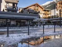 a street scene with a building and buildings reflecting in the water, and snow on the ground