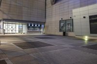 an outdoor patio at the back of a building at night with doors open in the middle