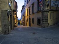 a street with stone walkways leading to buildings and windows at twilight overcast sky