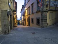 a street with stone walkways leading to buildings and windows at twilight overcast sky