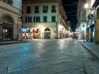 a narrow street with buildings lit up at night in europe, with cobblestones